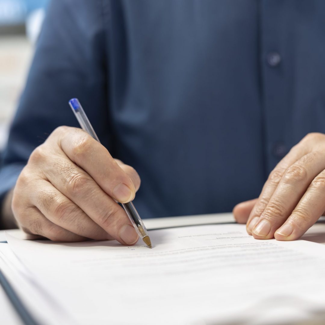 Senior man signing the financial contract with advisor expert, agreeing to terms for pension and life savings security. Mature person signs for life insurance policy. Close up.